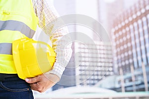 Close up backside view of engineering male construction worker stand holding safety yellow helmet