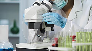 Close-up of bacteriologist viewing samples of bacteria on microscope, virology