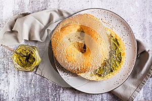 Close up of bagel with pistachio cream butter for breakfast on a plate on the table top view