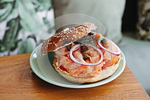 Close-up of a bagel topped with smoked salmon, red onion, and capers on a green plate