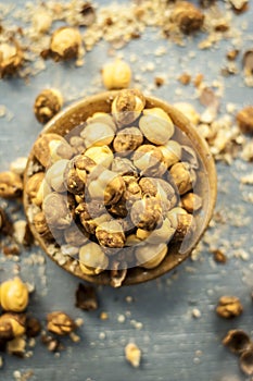 Close up of baked or roasted chickpea/channa or dalia in a bowl on a blue surface.