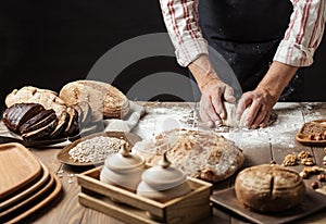 Close up of baker hands kneading dough and making bread with a rolling pin.