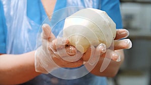 Close-up of baker`s hands in silicone gloves kneading the piece of dough to make some baked goods. Stock footage