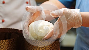 Close-up of baker`s hands in silicone gloves kneading the piece of dough to make some baked goods. Stock footage