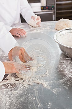 Close up of bakers kneading dough at counter