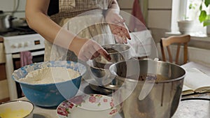 Close-up of bakery concept - Woman sift cocoa powder through metallic sieve to glass bowl