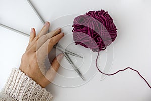 close-up of a ball of marsala yarn and two knitting needles in woman hand