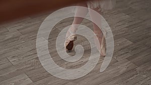 Close-up of a ballerina`s feet on pointe shoes, taking steps and stretching her feet before class