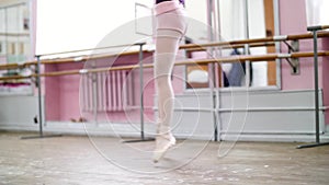 Close up, in ballet class, on an old wooden floor, ballerina performs glissade en tournant, She moving through the