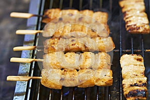 Close up of barbecue grill salmon skewers on wooden sticks, thai street food market