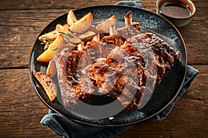 Close up of barbecued ribs and wedges on timber