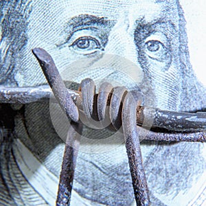 Close up barbed wire against US Dollar bill