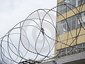 Close-up of the barbed wire on the fence. Building in the background. The concept of protecting borders from intrusion