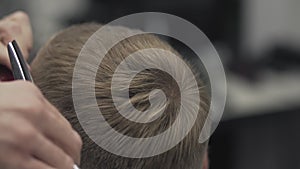 Close up barber cuts hair with scissors. Men`s hairstyling in barber shop