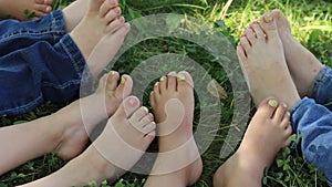 close up of bare feet on grass, top view. Kids sitting together