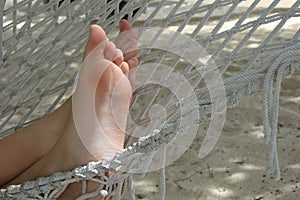 Close up on bare feet in a hammock on a beach