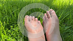 Close up of bare feet lying on a fresh green grass.