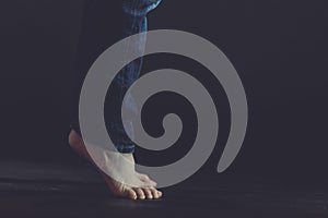 Close up of bare feet standing on dark floor