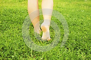 Female bare feet on mawed lawn grass. Young woman resting outdoors barefoot, take a break concept. Student on college campus yard.