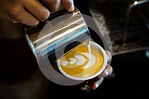 Close up barista hands pouring froth milk in espresso coffee cup for making latte art