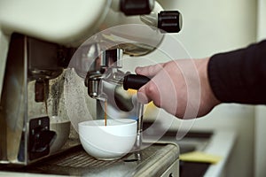 Close-up of barista`s hands making espresso in the professional coffee machine