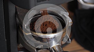 Close-up of a barista tempering ground coffee with a tempera in a coffee shop.