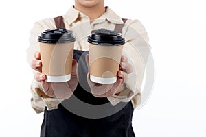 Close-up of a barista young asian woman in an apron presenting a takeaway coffee cup.