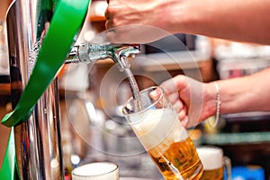 close-up of barman brewing a draft beer at pub. Bartender pourin photo