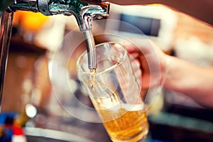 Close-up of barman hand at beer tap pouring a draught beer photo