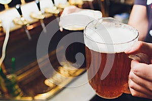 Close-up of barman hand at beer tap pouring a draught lager beer.