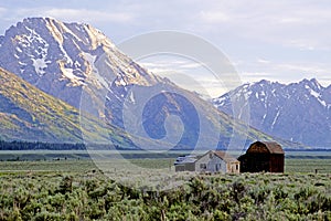 Close-up barn beneath snow-capped mountains.