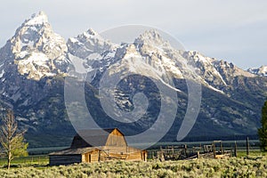 Close-up barn beneath snow-capped mountains.