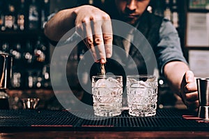 Close up of barman hands pouring sugar in old fashioned cocktail. fresh beverages at bar