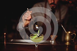 Close-up of bartender making green cocktail