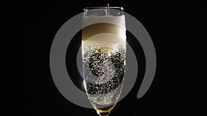 Close-up of the bartender pouring champagne into a glass on a black background.