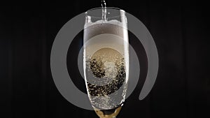 Close-up of the bartender pouring champagne into a glass on a black background.