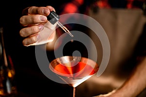 Close-up. Bartender`s hand adds cocktail ingredient using dropper