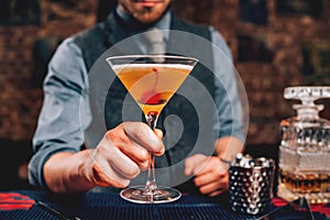 Close up of Bartender serving manhattan cocktail in martini glass