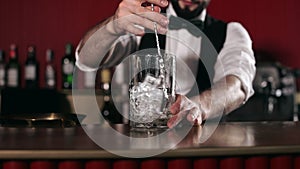 Close up of bartender stirring cocktail with ice cubes