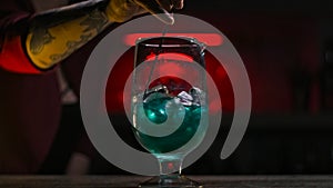 Close-up of bartender stirring cocktail with ice with spoon. Stock footage. Beautiful mixing with cocktail spoon of