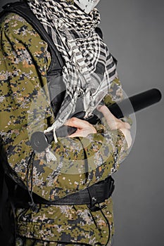 Close-up baseball bat in the hands of an unknown person in camouflage and body armor