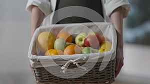 Close-up basket with organic vitamin healthful fruits in hands of unrecognizable pregnant woman. Positive Caucasian