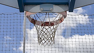 Close-up of a basketball hoop, red, in the open air, the blue sky with fluffy clouds in the background.