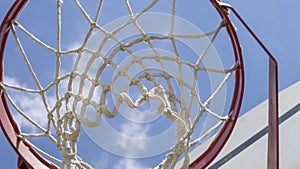 Close-up of a basketball hoop seen from below, blue sky in the background