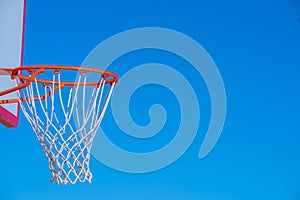 Close up on a basketball net against blue sky near sunset