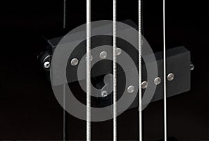 Close-up bass guitar pickups and strings. Musical instruments. Black guitar deck