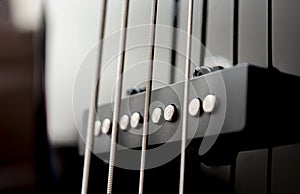 Close-up bass guitar pickups and strings. Musical instruments. Black guitar deck