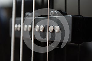 Close-up bass guitar pickups and strings. Musical instruments. Black guitar deck