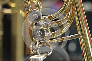 Close-up of a bass trombone tube with a fourth and fifth valve. Whorls in golden brass metal. Jazz trombones detail view with