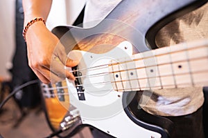 close up of a bassist& x27;s hand strumming electric guitar bass strings while checking sound